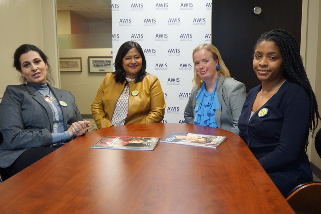 4 women sitting around a table together, in front of an AWIS background
