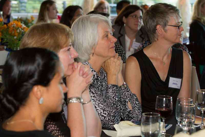 women at a table at a banquet, listening to a speaker